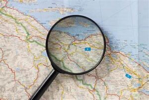 Magnifying glass on a world map, symbolizing search and location.