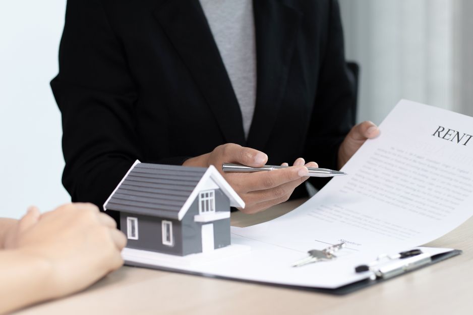 Two individuals seated at a table, examining a house model alongside a checklist for landlords.