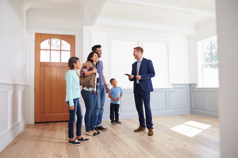 Smiling family viewing property with realtor in modern home interior.