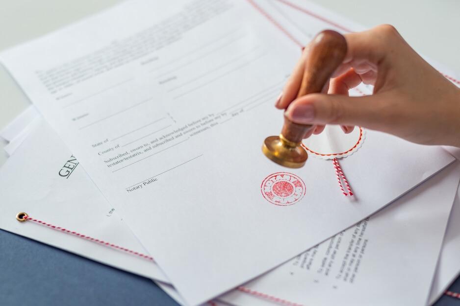 Close-up of notarization process with red stamp on legal documents.